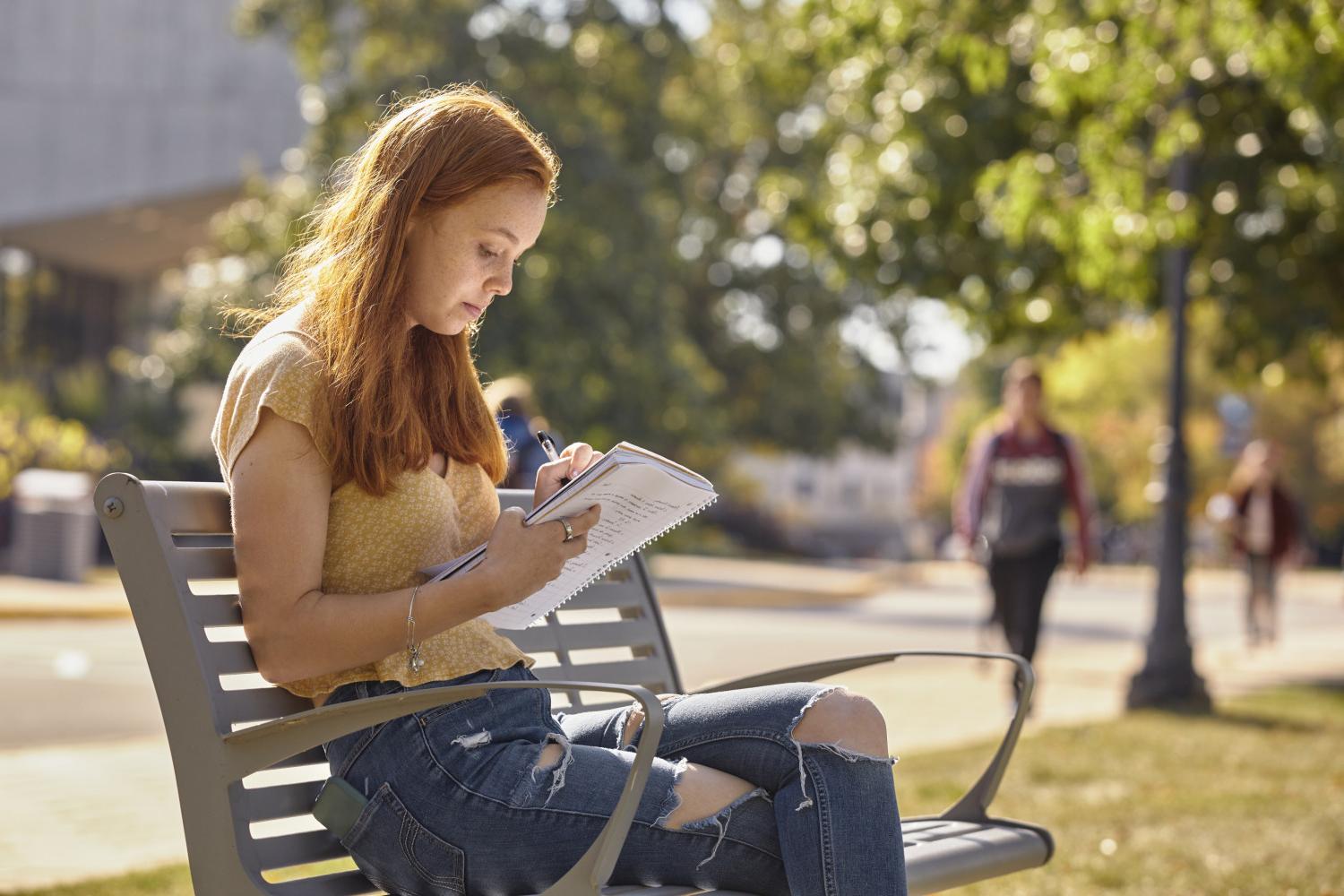 一位<a href='http://j.jiejuzhongxin.com/'>全球十大赌钱排行app</a>学院的学生在校园里的长椅上读书.